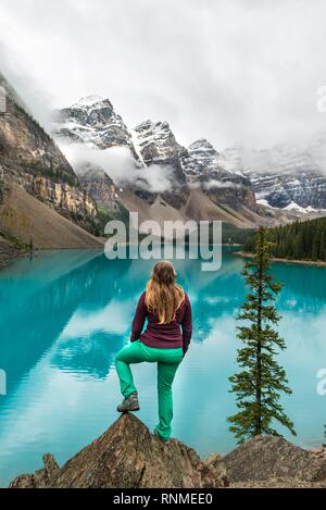 Junge Frau vor einem See in Bergwelt suchen, Wolken zwischen Bergspitzen, Reflexion in der türkisfarbenen See, Moräne La Stockfoto