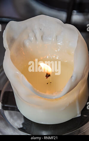 Brennende weiße Kerze, geschmolzene Wachs, die Flamme zu schließen. Stockfoto