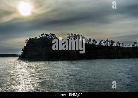 Moody Sonnenuntergang im Hauraki Gulf, Waiheke nach Auckland. Atemberaubende Landschaft, landspitze gegen die untergehende Sonne. Stockfoto