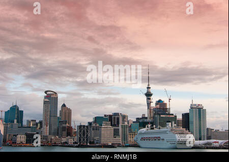 Auckland, Neuseeland - Juli, 2018: Die Skyline der Stadt mit P&O Kreuzfahrtschiffe Pacific Jewel neben den Wharf und bunten Sonnenuntergang Himmel Hintergrund Stockfoto