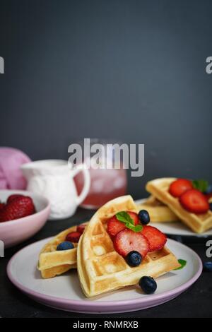 Frühstück mit hausgemachten belgischen Waffeln mit Beeren auf dunklen Moody Hintergrund, selektiver Fokus Stockfoto
