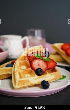 Frühstück mit hausgemachten belgischen Waffeln mit Beeren auf dunklen Moody Hintergrund, selektiver Fokus Stockfoto