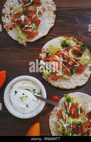 Hausgemachte Chicken Tikka soft Tacos mit saurer Sahne beträufelt, Ansicht von oben Stockfoto