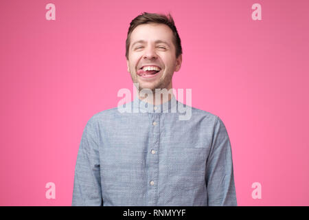 Sorglos attraktiver Kerl im blauen Shirt, Zunge und lustiges Gesicht Stockfoto