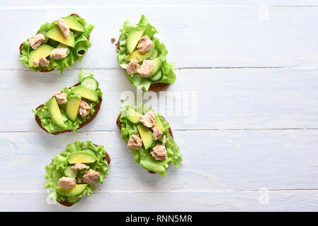 Thunfisch Sandwiches mit Avocado und Salatblätter über hellen Hintergrund mit kopieren. Lecker Thunfisch Brötchen zum Frühstück oder Mittagessen. Gesunde sn Stockfoto