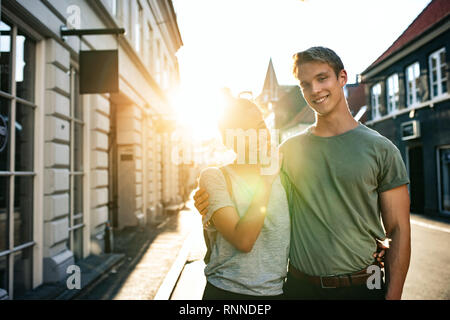 Porträt eines jungen Paares Lachen beim stehen Arm in Arm zusammen auf einer Straße der Stadt am Nachmittag Stockfoto
