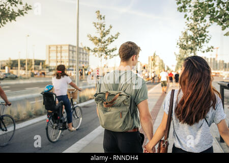 Die aussenspiegel von einem jungen Paar Hand in Hand zusammen eine Stadt bürgersteig am Nachmittag Stockfoto
