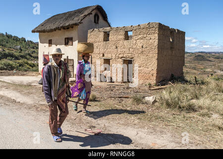 Tragen Ware auf dem Kopf + typischen Gebäude. Blick entlang der N7 in Ranomafana Antsirabe Madagaskar Stockfoto