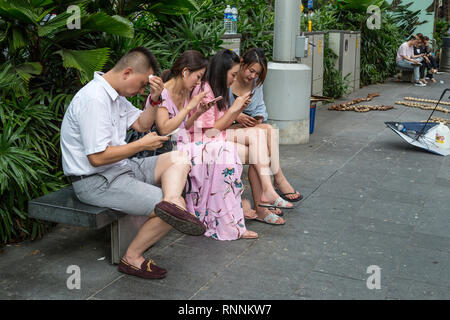 Von Singapur, der Orchard Road Street Scene, Fußgänger Überprüfung ihrer Handys. Stockfoto