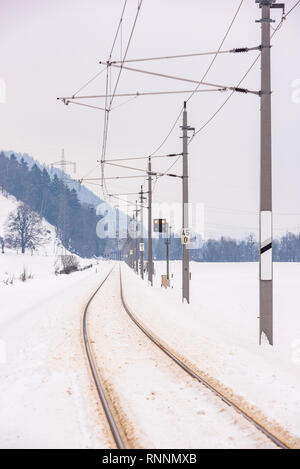 Bahn-Straße überqueren und die schneebedeckte Felder in einer malerischen Berglandschaft im Winter, Dachsteinmassiv, Bezirk Liezen, Steiermark, Österreich, Europa Stockfoto