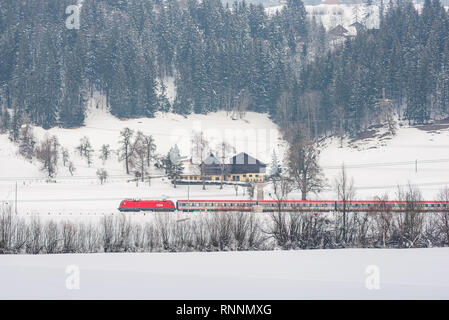 Rote und weiße Zug ÖBB bestehen der Schnee - Felder in einer malerischen Berglandschaft im Winter bedeckt, Dachsteinmassiv, Bezirk Liezen, Steiermark, Österreich Stockfoto