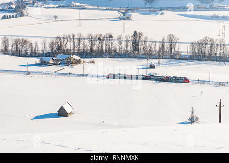 Rote und weiße Zug ÖBB bestehen der Schnee - Felder in einer malerischen Berglandschaft im Winter bedeckt, Dachsteinmassiv, Bezirk Liezen, Steiermark, Österreich Stockfoto