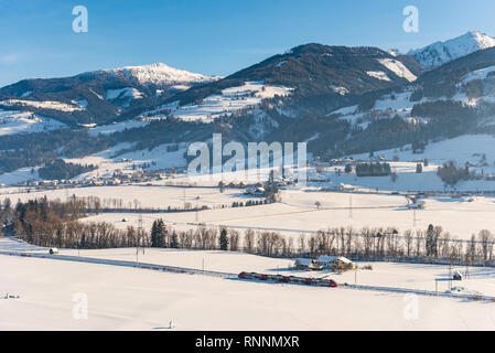 Rote und weiße Zug ÖBB bestehen der Schnee - Felder in einer malerischen Berglandschaft im Winter bedeckt, Bezirk Liezen, Steiermark, Österreich, Europa Stockfoto