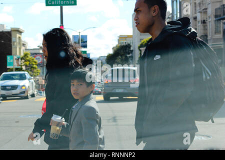 Ein Junge wendet sich zur Kamera, als er die Straße in der Stadt San Francisco, CA kreuzt. Stockfoto