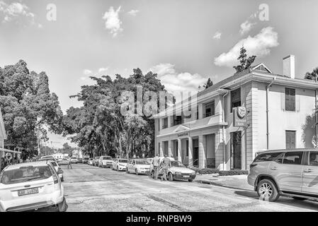 CLANWILLIAM, SÜDAFRIKA, 22. AUGUST 2018: eine Straße, Szene, mit einer Bank, Personen und Fahrzeuge, in Clanwilliam in der Western Cape Provinz. Schwarzweiß Stockfoto