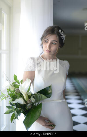 Eine junge nachdenklich Paare haben einen traditionellen englischen White Wedding, sie sind beide dunkle Haare und gut aussehende, scheinen aber unglücklich Stockfoto