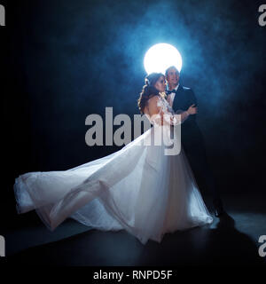 Geheimnisvoll und romantisch, die Braut und der Bräutigam unter dem Mond. Umarmungen zusammen. Mann und Frau, Hochzeit Kleid. Mixed Media. Stockfoto