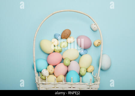 Blick von oben auf die bemalte Ostern Hühner und Wachteln Eier im Stroh Korb Stockfoto