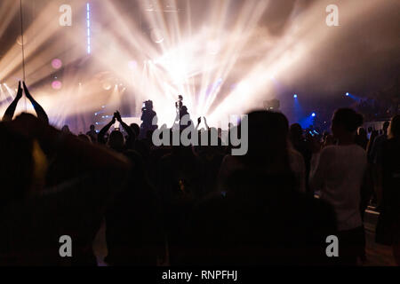 Silhouetten von einem Konzert Masse und Kameramann vor dem Hintergrund der hellen, farbigen Strahlen auf die Bühne. Kamera mit dem Operator ist auf der Pla Stockfoto