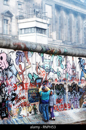 Westdeutsche Kinder versuchen, Chip, ein Stück der Berliner Mauer als Souvenir. Ein Teil der Mauer wurde bereits am Potsdamer Platz abgerissen. Stockfoto