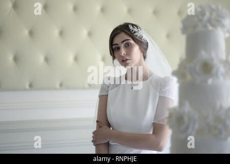 Eine junge nachdenklich Paare haben einen traditionellen englischen White Wedding, sie sind beide dunkle Haare und gut aussehende, scheinen aber unglücklich Stockfoto