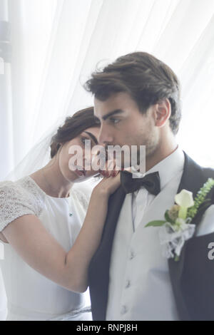 Eine junge nachdenklich Paare haben einen traditionellen englischen White Wedding, sie sind beide dunkle Haare und gut aussehende, scheinen aber unglücklich Stockfoto