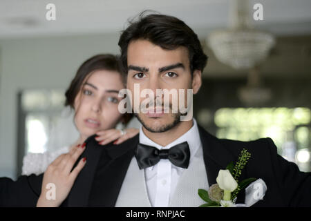 Eine junge nachdenklich Paare haben einen traditionellen englischen White Wedding, sie sind beide dunkle Haare und gut aussehende, scheinen aber unglücklich Stockfoto
