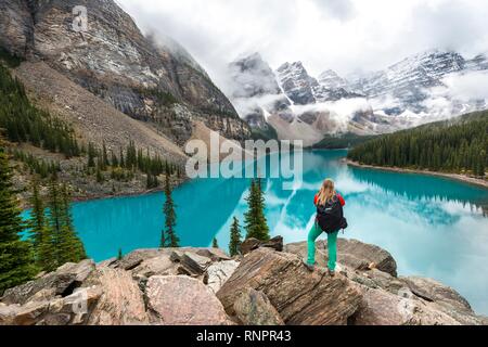 Junge Frau vor einem See in Bergwelt suchen, Wolken zwischen Bergspitzen, Reflexion in der türkisfarbenen See, Moräne La Stockfoto