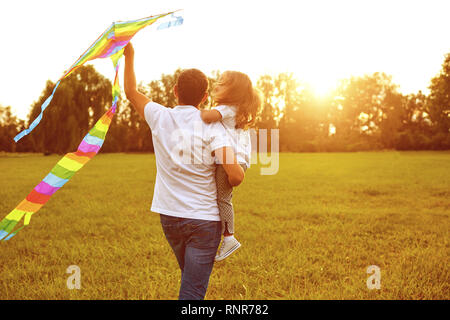 Glückliche Familie Vater und Kind laufen auf Wiese mit einem Drachen im Sommer auf der Natur Stockfoto