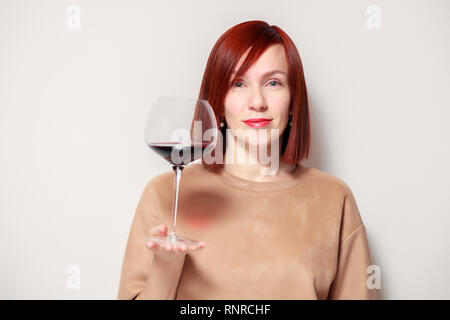 Junge schöne rothaarige Mädchen Sommelier mit Hellen Lippenstift auf weißen Hintergrund ist und lächelnd Glas Rotwein an professionelle blinde Tasten Stockfoto