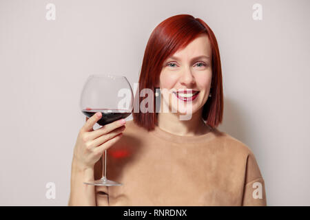 Junge schöne rothaarige Mädchen Sommelier und lächelnd Glas Rotwein am professionellen Blindverkostung sommelier Wettbewerb. Konzept Alkoholismus Stockfoto