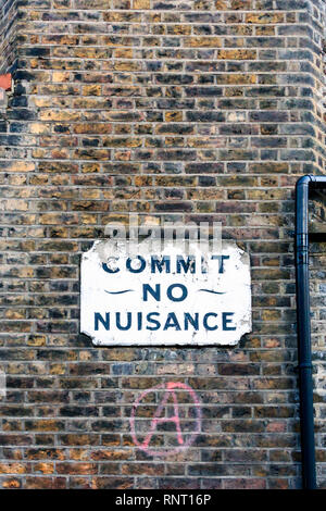 Ein altes Schild 'Commit keine Belästigung', unten eine rot lackierte Anarchie Zeichen, auf der Mauer eines Mietshauses in Southwark, London, UK Stockfoto