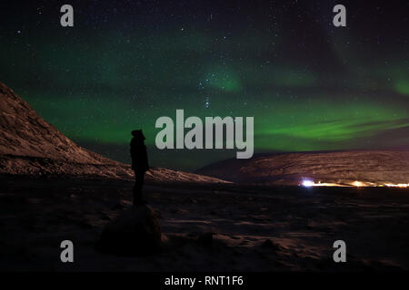 Am Straßenrand nur außerhalb der Inuit Gemeinschaft, Pangnirtung auf Baffin Island. Aurora Borealis sichtbar in Richtung der Stadt. Stockfoto