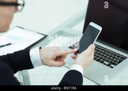 Aus der Nähe. Ein Geschäftsmann verwendet ein Smartphone am Arbeitsplatz Stockfoto