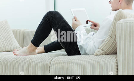 Seitenansicht. Moderne Kerl lesen Ein e-Buch sitzen auf der Couch in seinem Wohnzimmer Stockfoto