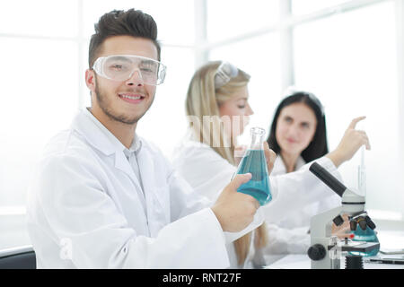 Mann Wissenschaftler aus einem Gefäß Flüssigkeit für das Experiment Stockfoto