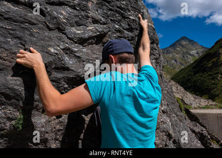 Jungen kaukasischen Mann ist Klettern auf einem Felsen in der Schweiz Stockfoto