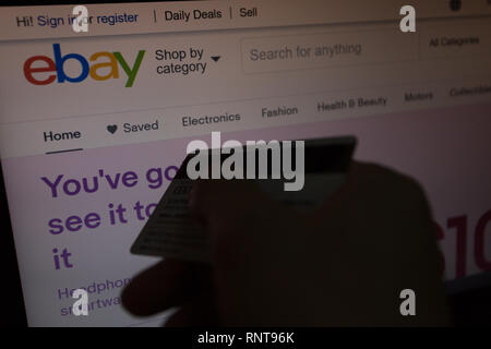 EBay Logo auf Ihrer Website auf Laptop Computer Bild angezeigt wird, mit der Hand, die eine Kreditkarte Debitkarte unfocused auf vorne, On-line-Käufer, Einkäufe Stockfoto