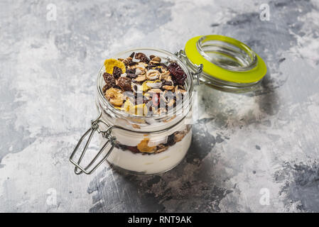 Horizontale Foto von weißen Joghurt. Joghurt ist in kleinen Glas Glas mit Metall- und versiegelt. Müsli mit getrockneten Essen ist in und auf Joghurt geschichtet. G Stockfoto