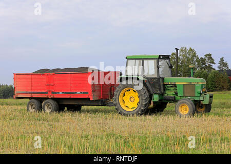 Salo, Finnland - 8 September, 2018: John Deere 3140 farm Traktor im Feld vor der landwirtschaftlichen Anhänger mit Ladung der geernteten Raps im Herbst. Stockfoto