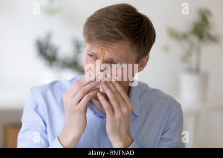 Mann hält Papiertaschentuch und blasen Nase Stockfoto