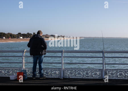 Ein Mann Strand Angeln aus einem alten viktorianischen Pier an der britischen Küste Stockfoto