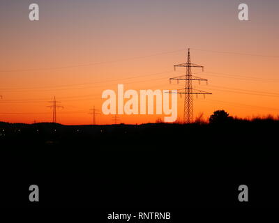 Bild von Silhouetten von Strommasten in der Landschaft bei Sonnenuntergang Stockfoto