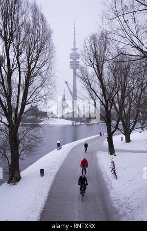 Drei Radfahrer Fahrt entlang eines Pfades im Olympiapark in München, Deutschland, an einem Wintertag Stockfoto