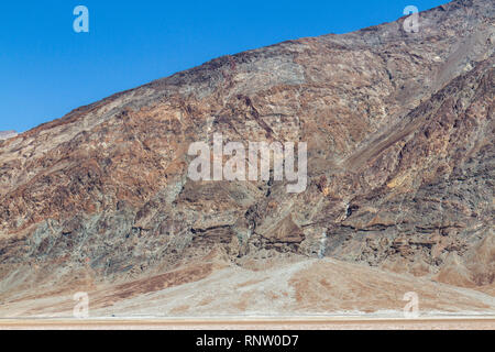 Autos entlang Badwater Road vor dem Fuß des Mt Perry, Badwater Basin, Death Valley National Park, California, United States. Stockfoto