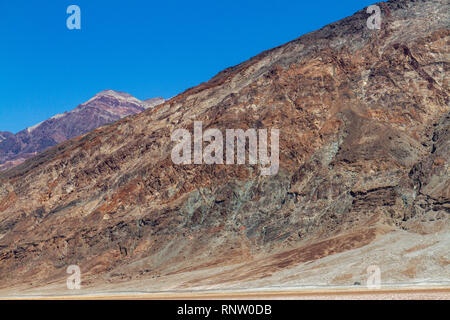 Autos entlang Badwater Road vor dem Fuß des Mt Perry, Badwater Basin, Death Valley National Park, California, United States. Stockfoto