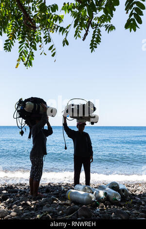 Zwei Frauen schwer tragen, scuba diving Gear auf dem Kopf, einen gemeinsamen Standort in Tulemban, Bali, Indonesien. Stockfoto
