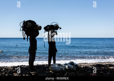 Zwei Frauen schwer tragen, scuba diving Gear auf dem Kopf, einen gemeinsamen Standort in Tulemban, Bali, Indonesien. Stockfoto