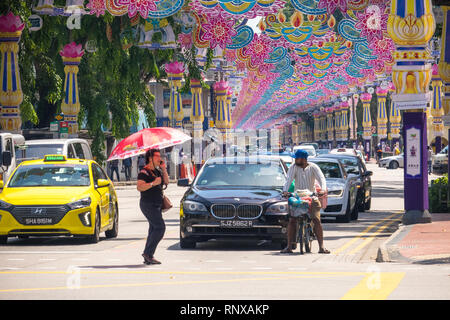 Frau mit Sonnenschirm am Telefon sprechen beim Überqueren der Straße an Deepavalie Festival - Little India, Singapur Stockfoto