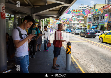 Fahrgäste des Busses neben Auto Verkehr auf Serangoon Rd warten, während Deepavali Festival in Llittle Indien - Singapur Stockfoto